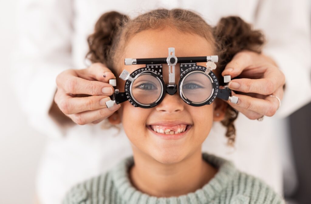 A young child has their vision tested by an optometrist using trial lenses.